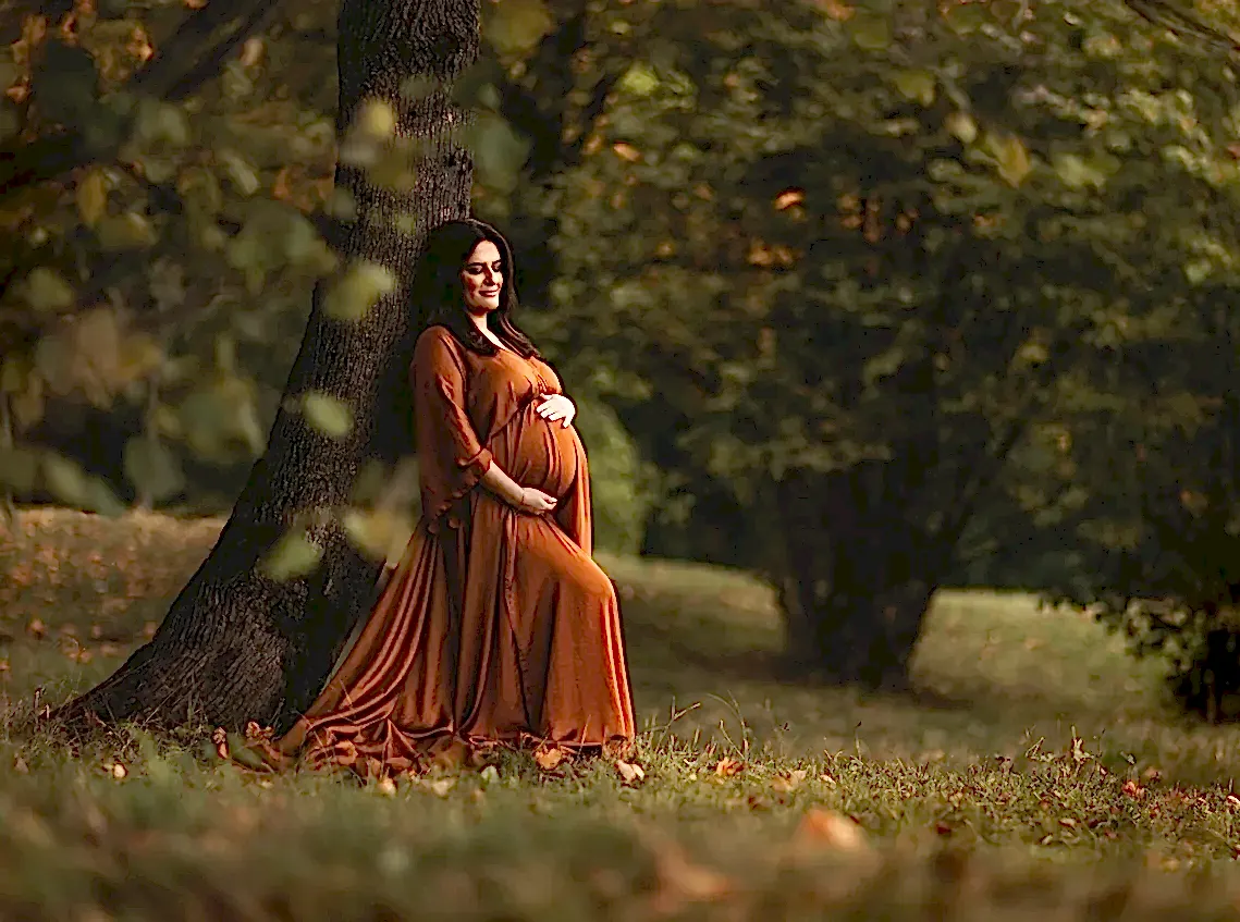 Gravid kvinne i oransje kjole i naturen
