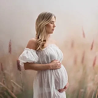 Gravid kvinne står i eng