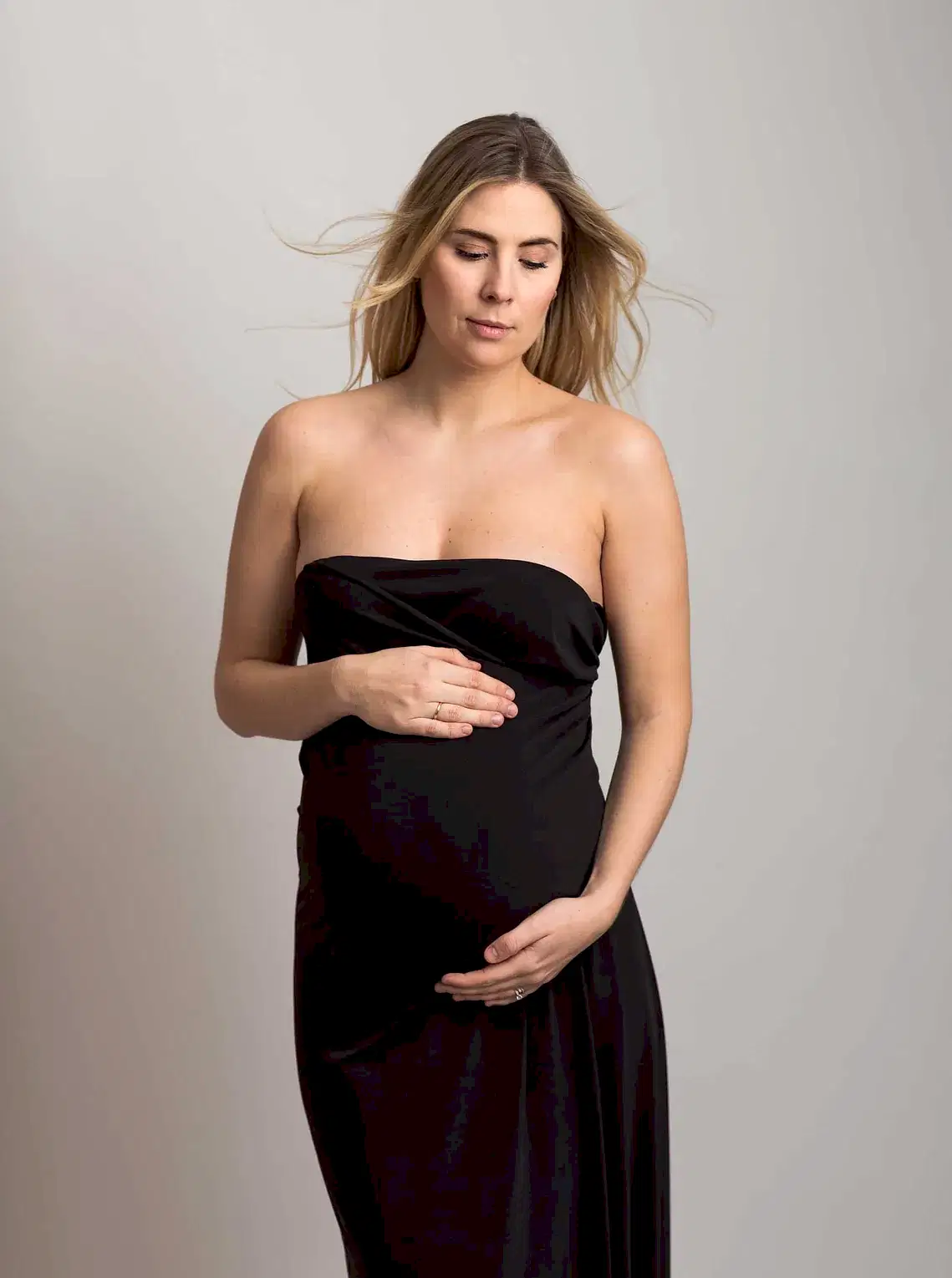 Gravid kvinne i svart stropløs kjole