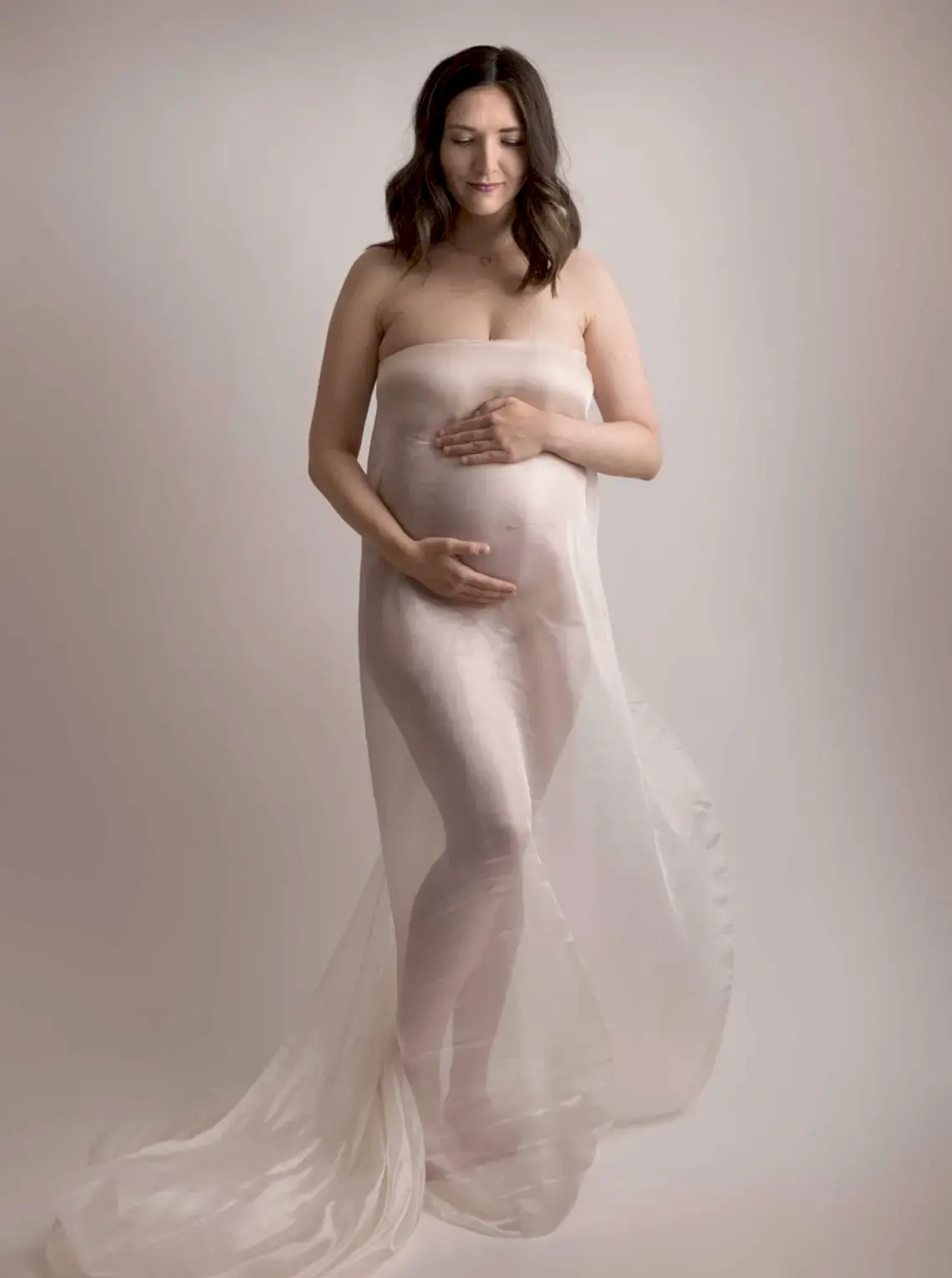 Gravid kvinne i gjennomsiktig hvit kjole